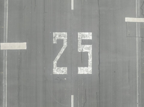 Aerial view of Landebahn Neubiberg runway with the number 25 painted on the asphalt surface in Unterhaching, Bavaria, Germany.