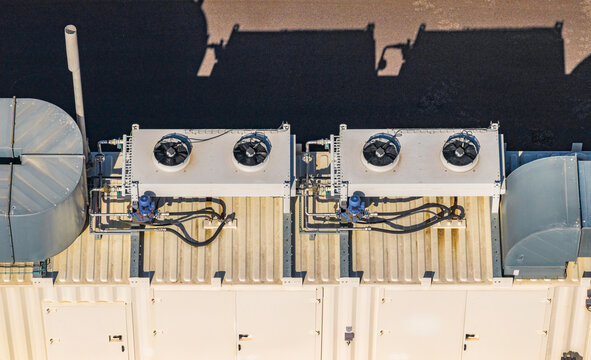 Aerial view of industrial HVAC cooling units with condenser fans, pumps, and ventilation ducts on a metal rooftop in Le Pouzin, Auvergne-Rhone-Alpes, France.