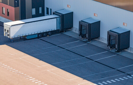 Aerial view of logistics warehouse loading docks with a semi-trailer parked at a bay and empty bays, showing freight distribution in Le Pouzin, Auvergne-Rhone-Alpes, France.