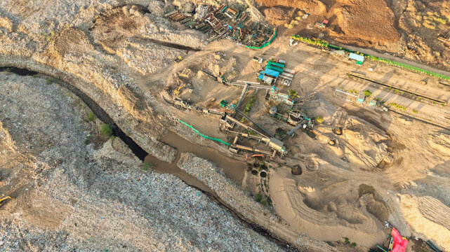 Aerial view of waste segregation and recycling facility with conveyor belts and sorting machinery at a landfill site in India.