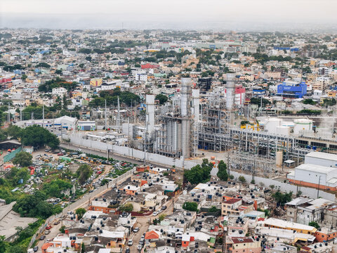 Aerial view of Parque Electrico Los Mina power plant with tall industrial chimneys and infrastructure amidst a dense urban landscape in Santo Domingo, Santo Domingo, Dominican Republic.