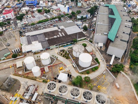 Aerial view of Parque Electrico Los Mina power plant with white storage tanks, cooling towers, and industrial buildings in Santo Domingo, Santo Domingo, Dominican Republic.
