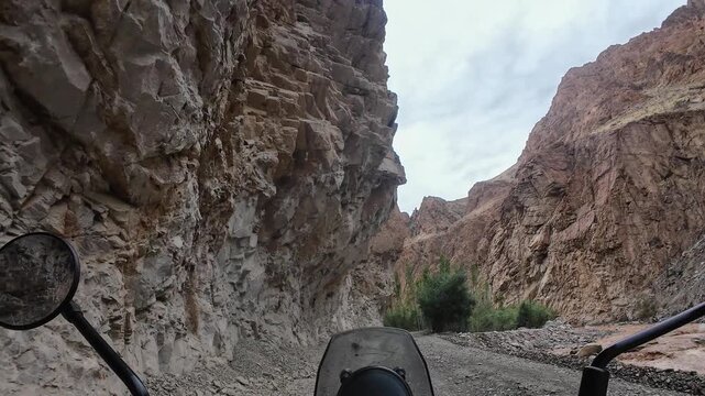 Dah anuh valley, India : Point of view footage of motorcycle rides on rocky off road in Aryan valley in Ladakh, India surrounded by arid mountain under dramatic cloudy sky