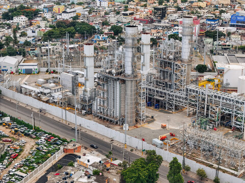 Aerial view of Parque Electrico Los Mina power plant with tall chimneys and industrial infrastructure surrounded by urban buildings and roads in Santo Domingo, Santo Domingo, Dominican Republic.