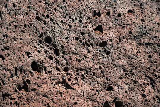 Full frame close-up of porous red volcanic lava rock texture with vesicular holes, resembling Mars terrain, an ideal background for design projects, Teide, Tenerife, Canary Islands, Spain.