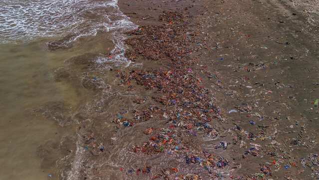 Aerial view of a beach heavily polluted with plastic waste and debris washed up by ocean waves in Indonesia.