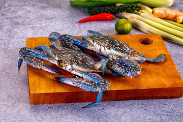 Blue crabs on wooden cutting board with fresh herbs and spices © Andrei Starostin