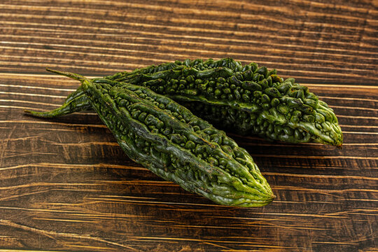 Two green bitter gourds on rustic wooden surface