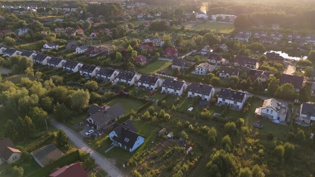 Aerial high-angle drone shot of suburban neighborhood and residential housing estates during sunset, highlighting real estate development and urban planning.