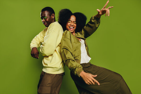 On a green background, friends dance in the studio with playful movement and youth