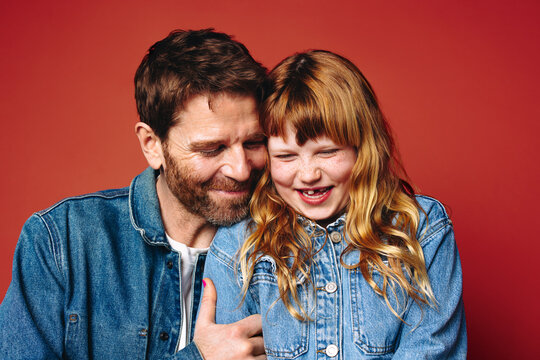 A warm studio scene, family love surrounds a father and daughter smiling together