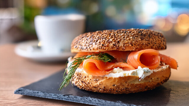 Smoked salmon bagel with cream cheese and blurred brunch cafe background banner.