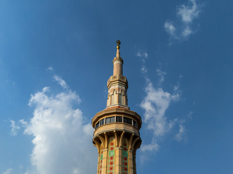 Aerial view of the minaret of Al Aqsha Great Mosque Klaten with ornate patterns and a golden spire against a clear blue sky in Kecamatan Klaten Utara, Jawa Tengah, Indonesia.