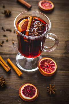 mulled wine with spices in cup on wooden background