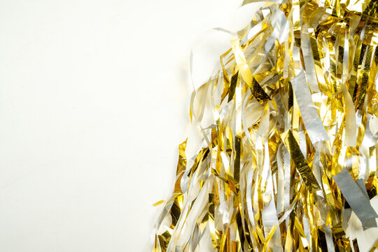 Festive background featuring shiny gold metallic foil tinsel streamers. Holiday or celebration background