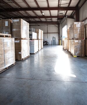 Rows of shipping pallets containing kennel materials sit ready for transport in a bright warehouse