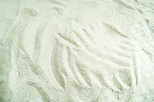 Smooth, wavy patterns carved in fine white sand, creating a minimalist textured background. Summer, natural or texture background