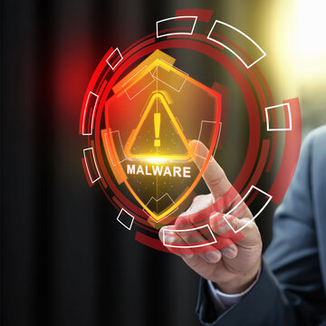 Businessman touching a virtual shield displaying a malware warning, representing cybersecurity threats and data protection. Cybersecurity concept
