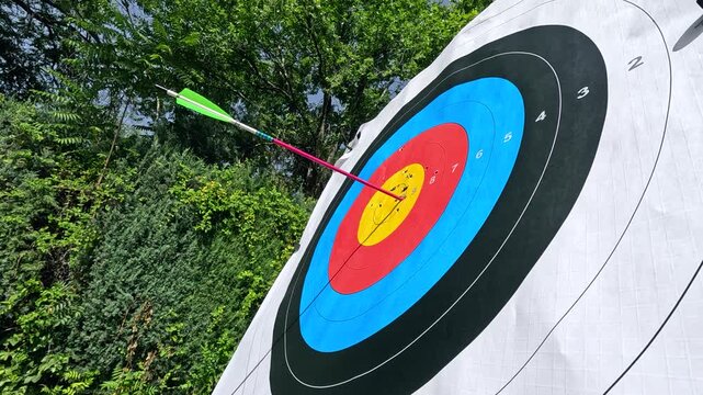 Close up of arrows hitting the yellow bullseye of a colorful target during an archery practice session. Precision and accuracy in sport