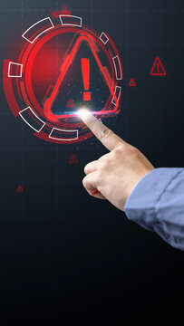 Businessman pointing at a glowing red warning triangle icon on a digital interface, symbolizing cybersecurity alert, system error, or risk management on a dark background. Cyber threat concept