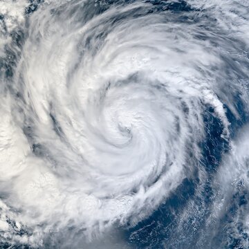 Close satellite-style view of a powerful tropical cyclone swirling above the ocean, showing dense cloud bands for weather forecasting, storm tracking and disaster risk content