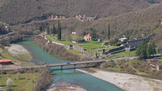 Static aerial drone reveal of the ancient Nokalakevi Fortress perched above a scenic winding river, showcasing the lush green countryside and historic landscape of Samegrelo, Georgia.