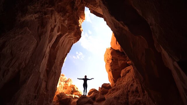 Woman Standing on Rock at Entrance of Big Cave Under Sandstone Formations. Goblin's Lair Trail, Utah USA