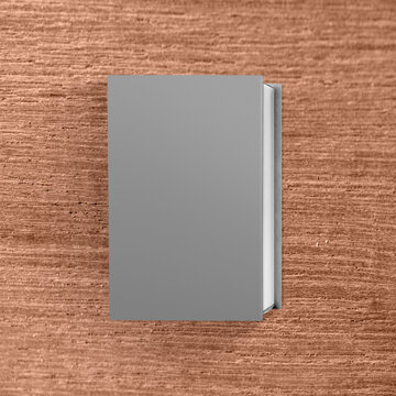 Top view of a blank grey hardcover book mockup on a textured brown wooden background. Mockup or Copyspace