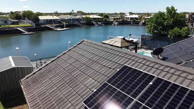 Modern solar panels installed on a residential roof in a sunny waterfront neighborhood. Sustainable photovoltaic system producing clean electricity. In queensland australia