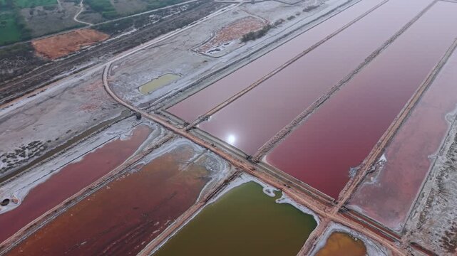 Aerial view shows rectangular evaporation ponds filled with pink and red salt water at Sambhar Salt Lake, India's largest inland salt lake. The geometric salt pans are separated by earthen.