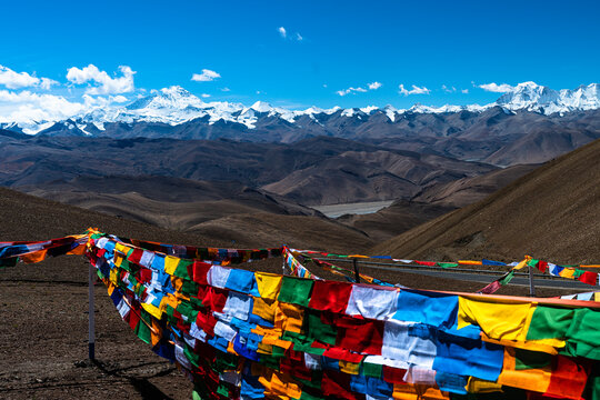 Colorful Tibetan prayer flags blowing in wind with snow covered Himalayan mountains background