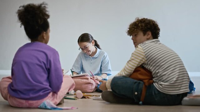 Multiethnic school children sitting on floor of art gallery, drawing in sketchbooks and discussing artwork. Perfect for school advertisements, museum promotions, and creative learning campaigns