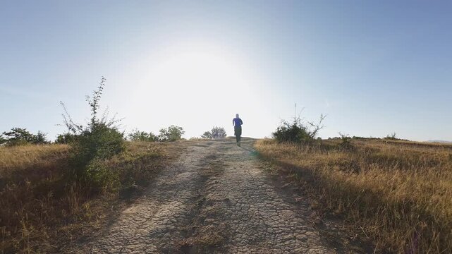 Woman trail running solitary across rural steppe forward tracking shot