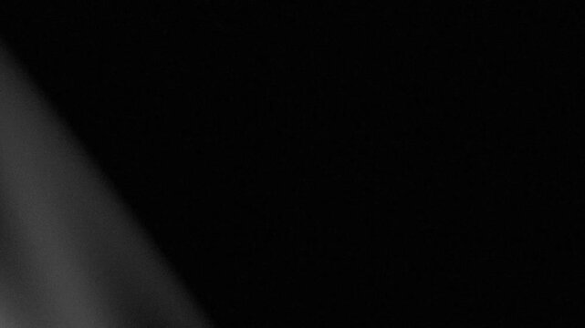 Abstract black background with subtle diagonal light rays and texture