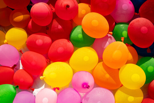 Full frame background of colorful water balloons under bright sunlight