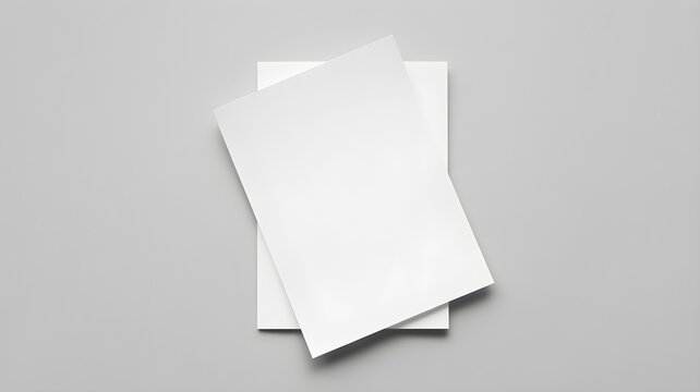Top view of two blank white paper sheets stacked on a grey background.