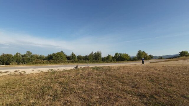 Trail running woman hijab determined athlete across rural grassland wide angle