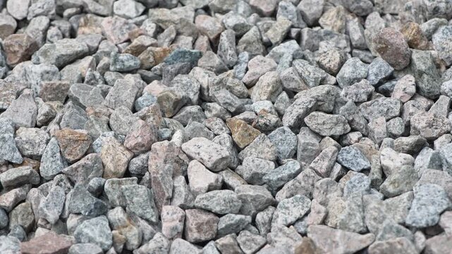 Close up footage of grey and pink granite gravel on ground surface.