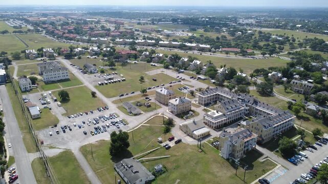 Sprawling masonry compound borders open South Texas airfield near Broadway corridor. Distinct gabled barracks overlook large vehicle lots, access drives, sunny lawns, San Antonio