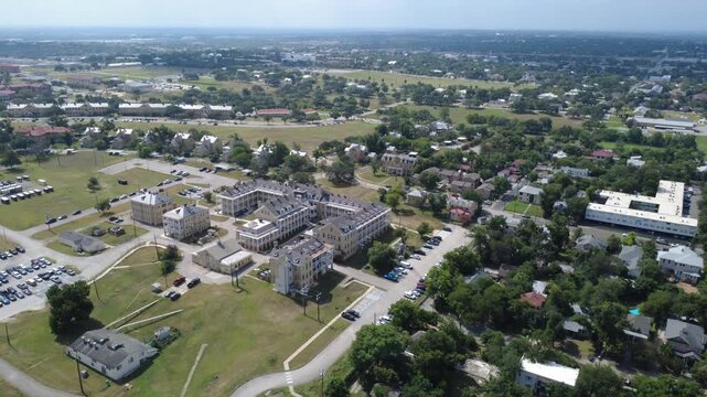 Historic limestone barracks frame Mahncke Park in Bexar County border near Broadway. Classic multi wing military buildings overlook large vehicle lots, access drives, wide lawns, San Antonio, TX