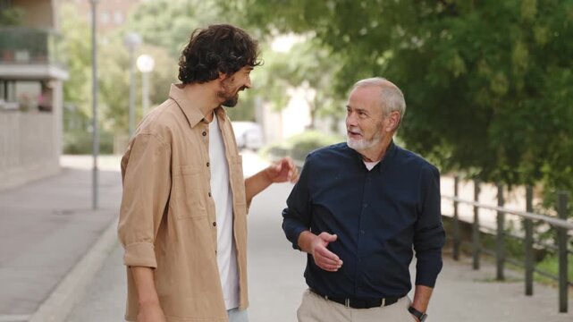 Happy senior father with his son walking and embracing in the city. Smiling, talking. Family love, bonding 
