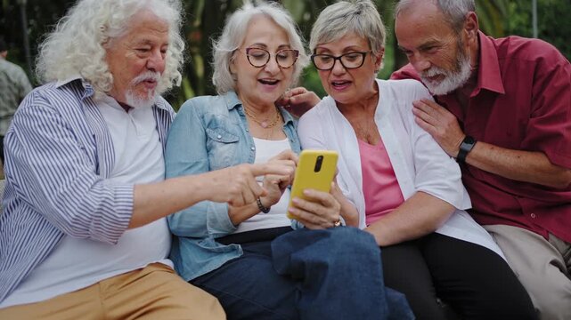 Funny senior friends using smartphone sharing content on social media having fun together