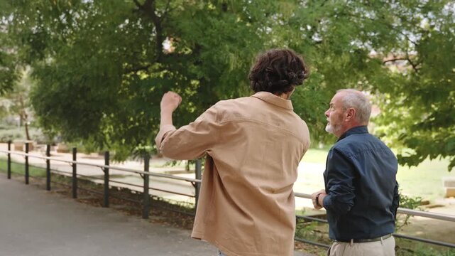 Senior father and his adult son walking pin the city park, talking about future plans and projects. Family bonding