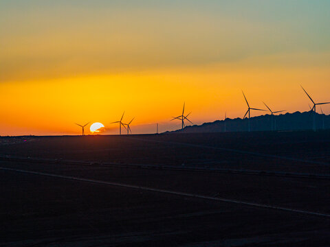 Solar photovoltaic panels at sunrise/sunset; wind turbine power plant; new energy