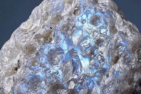 Moonstone crystal macro with iridescent schiller effect on solid slate blue background