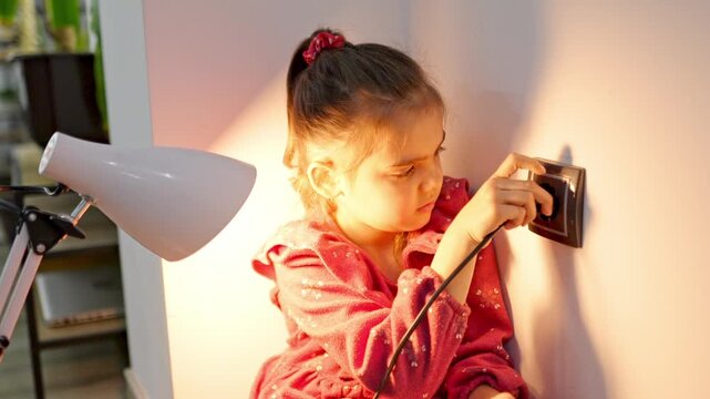 Curious girl plugging lamp into wall socket