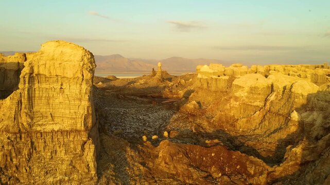 Aerial view of the geothermal area of Dalol with colorful mineral formations, salt deposits, and rugged terrain under golden hour light in Dalol, Afar, Ethiopia.