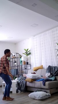Young woman doing squats in messy living room