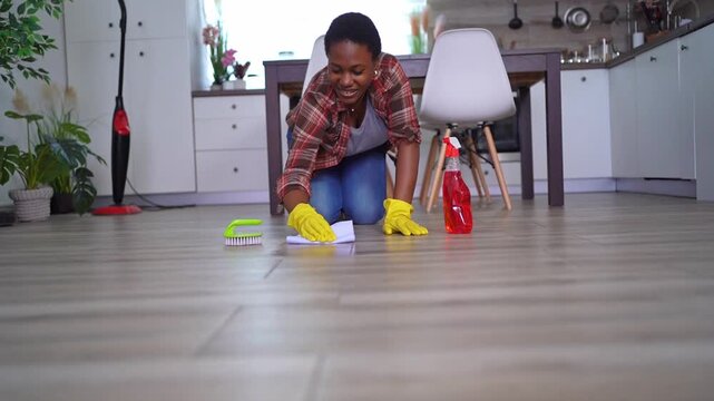 Woman cleaning kitchen floor with rag and detergent