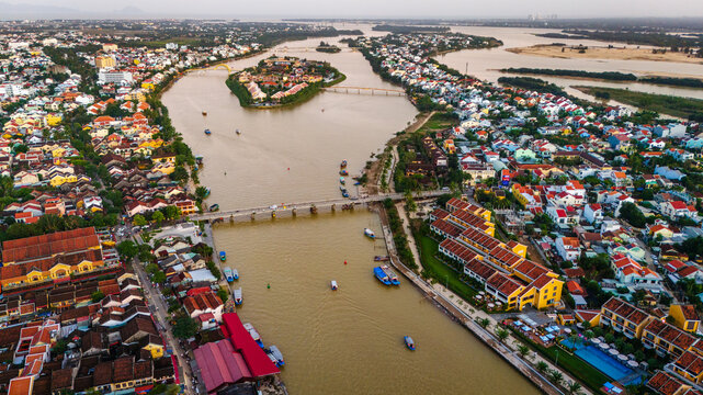 Aerial view of Hoi An with its iconic yellow buildings, traditional bridges, and boats navigating the Thu Bon River in Hoi An, Da Nang, Vietnam.